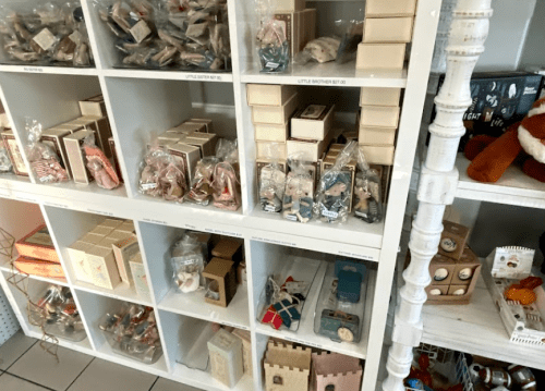 Shelves filled with neatly arranged packaged items, including toys and small gifts, in a retail display.