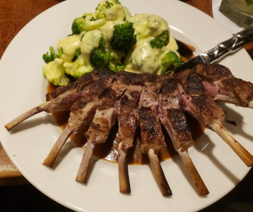 A plate featuring grilled lamb chops with a side of broccoli in creamy sauce.