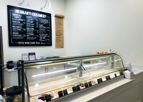 Interior of Negranti Creamery featuring a menu board and a display case with various ice cream flavors.