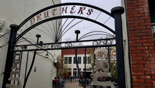 Entrance gate of Druthers Brewing Co., featuring decorative metalwork and a view of the outdoor seating area.