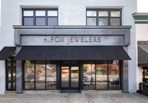 Exterior of n.FOX Jewelers, featuring large windows and a modern sign, with an awning over the entrance.