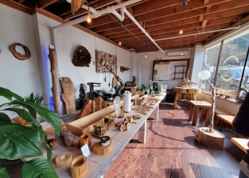 A cozy artisan shop showcasing wooden crafts, sculptures, and decor under warm lighting and a rustic ceiling.