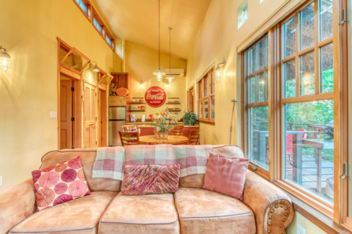 Cozy living space with a brown couch, colorful pillows, and a view of a kitchen with a Coca-Cola sign.