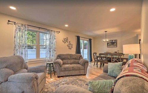 Cozy living room with two sofas, a dining area, and large windows letting in natural light.