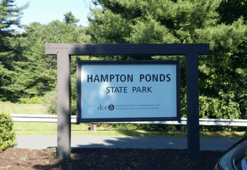 Sign for Hampton Ponds State Park, surrounded by greenery and trees, indicating the park's location in Massachusetts.