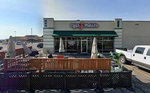 Exterior view of Cajun Phatties restaurant with outdoor seating and a green awning on a sunny day.