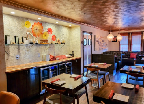 Cozy restaurant interior with wooden tables, stylish decor, and a decorative wall featuring colorful flowers.