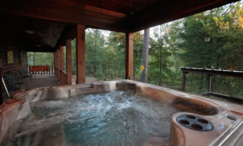 A hot tub on a wooden porch surrounded by trees, with a peaceful outdoor view.