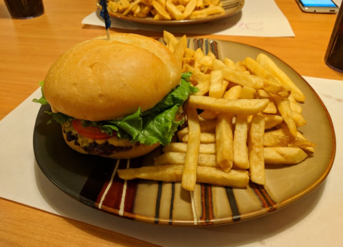 A plate with a burger topped with lettuce and tomato, accompanied by a side of golden French fries.