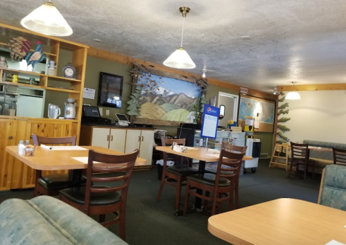 Cozy diner interior with wooden furniture, a mural, and a service area in the background. Bright lighting and a welcoming atmosphere.