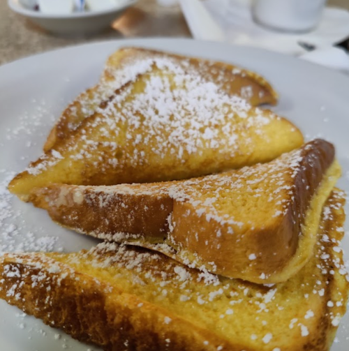Three slices of French toast dusted with powdered sugar on a white plate.