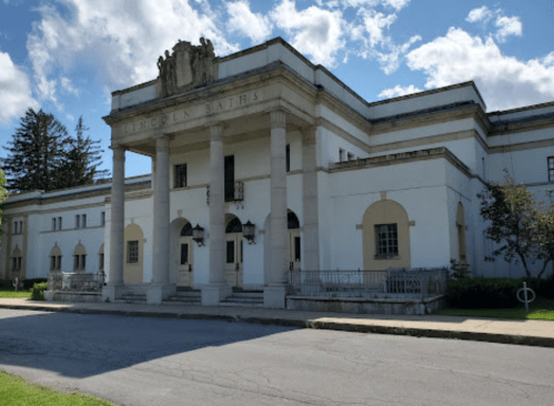 Historic building with classical architecture, featuring columns and decorative elements, set against a blue sky.