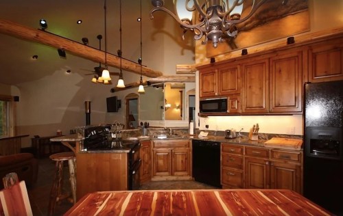 Cozy kitchen with wooden cabinets, modern appliances, and a rustic chandelier, featuring a warm, inviting atmosphere.