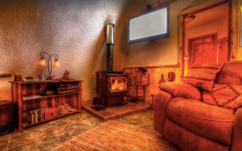 Cozy living room with a wood stove, TV, and comfortable seating, featuring warm lighting and rustic decor.