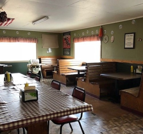 A cozy diner interior with wooden booths, a checkered tablecloth, and green walls adorned with decor.