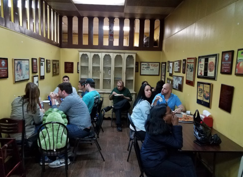 A cozy restaurant interior with patrons seated at tables, surrounded by framed photos and memorabilia on the walls.