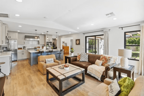 Bright, modern living room with a brown leather sofa, coffee table, and open kitchen in a spacious layout.