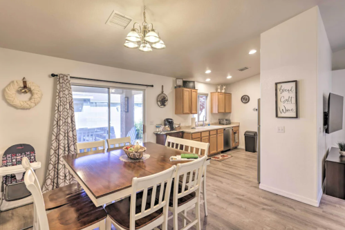 Bright kitchen and dining area with a wooden table, white chairs, and sliding glass doors leading to an outdoor space.