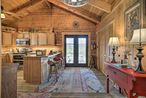 Cozy wooden cabin interior featuring a kitchen, dining area, and large glass doors leading to an outdoor view.