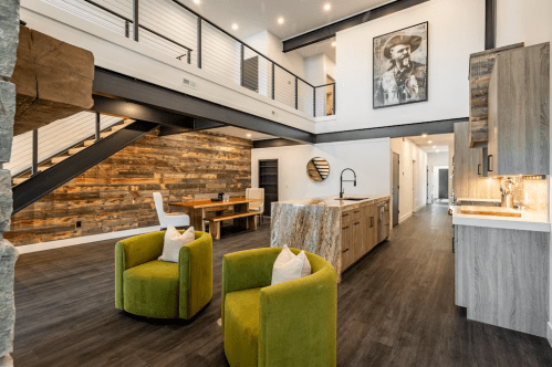 Modern open-concept living space featuring green chairs, a wooden dining table, and a stylish kitchen with an island.