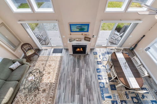 A spacious living area with a fireplace, dining table, and large windows, featuring a cozy rug and modern decor.