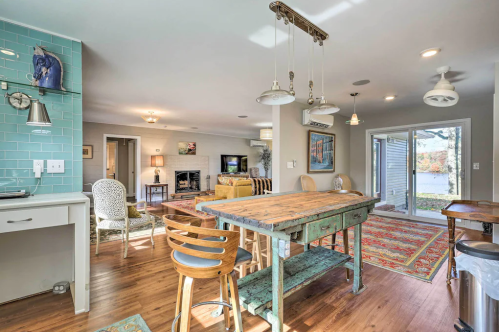 Bright, modern dining area with a rustic table, chairs, and large windows overlooking a scenic view.