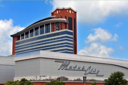 Exterior view of the MotorCity Casino Hotel, featuring a modern design against a blue sky with clouds.