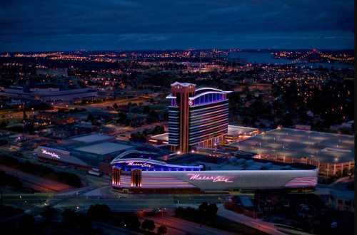 Aerial view of a brightly lit casino at night, surrounded by a cityscape and distant lights.