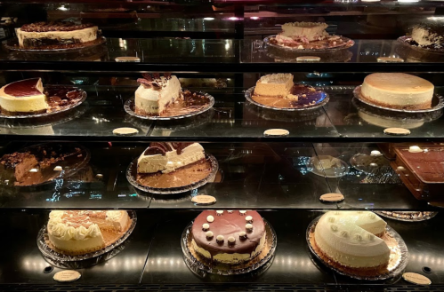 A display case filled with various cakes, including cheesecakes and chocolate desserts, beautifully arranged.