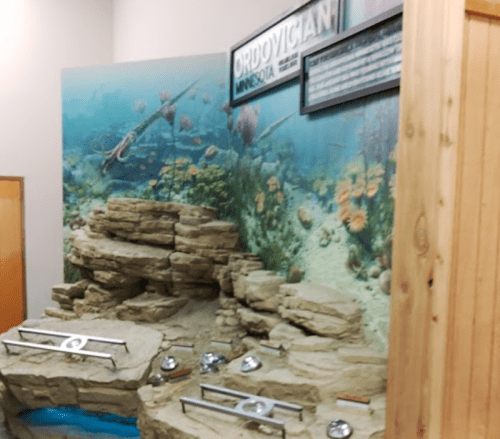 Display of an underwater scene from the Ordovician period, featuring rocks and marine life illustrations.