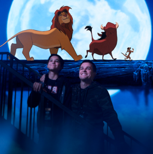 Two boys smile while standing on stairs, with animated characters from "The Lion King" against a full moon backdrop.
