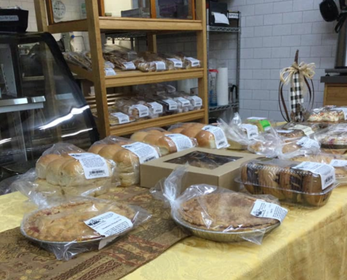 A display of assorted baked goods, including rolls, pies, and cookies, arranged on a table in a bakery.
