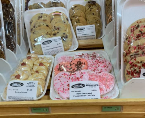 A display of assorted cookies, including spritz cookies and hand-decorated heart cut-outs with pink frosting and sprinkles.