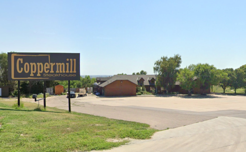 Sign for Coppermill Steakhouse with a view of the restaurant and surrounding area on a clear day.