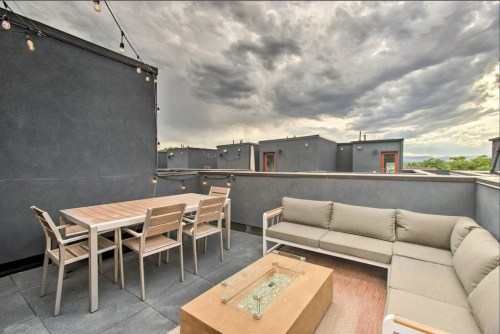 Rooftop patio with a dining table, seating area, and string lights under a cloudy sky.