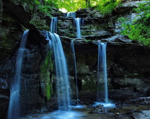A serene waterfall cascading over rocky cliffs, surrounded by lush green foliage.