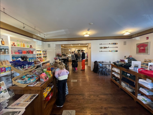 A cozy shop interior with shelves of snacks and drinks, people browsing, and a warm, inviting atmosphere.