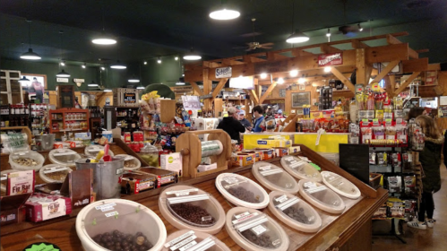 A bustling store interior filled with various snacks, candies, and goods, featuring wooden shelves and a warm atmosphere.