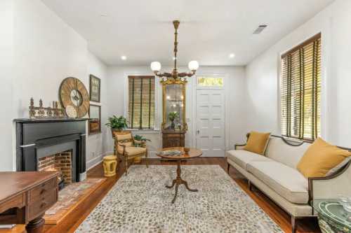 Cozy living room with a fireplace, vintage decor, a round table, and a sofa adorned with yellow cushions.