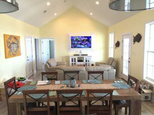 Bright living space with yellow walls, a dining table, leather sofas, and an aquarium on the wall.