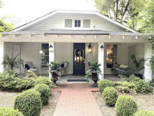 A charming house with a front porch, surrounded by greenery and neatly trimmed bushes, inviting and well-maintained.