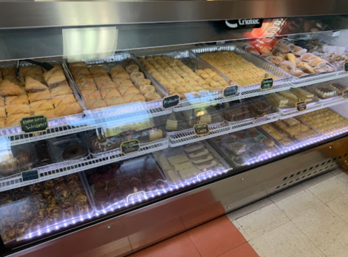 A display case filled with various pastries and desserts, including baklava and sweet rolls, neatly arranged.