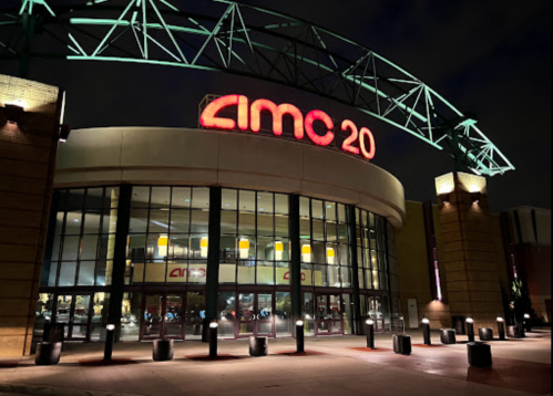 Exterior of an AMC 20 movie theater at night, featuring bright red signage and a modern architectural design.