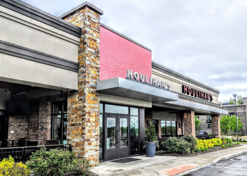 Exterior view of a Houlihan's restaurant featuring stone accents and a pink wall.