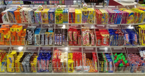 A colorful display of various candy bars and sweets arranged in clear bins at a store.