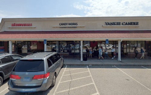 A shopping plaza featuring Aeropostale, Candy Works, and Yankee Candle, with a parked van in the foreground.