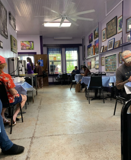 A cozy restaurant interior with purple walls, checkered tablecloths, and patrons enjoying their meals.