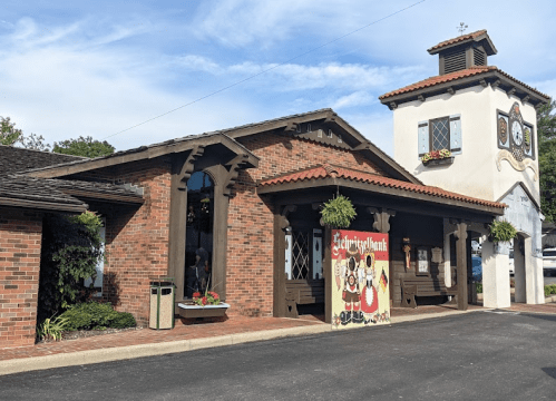 A charming brick building with a clock tower and decorative signage, surrounded by greenery.