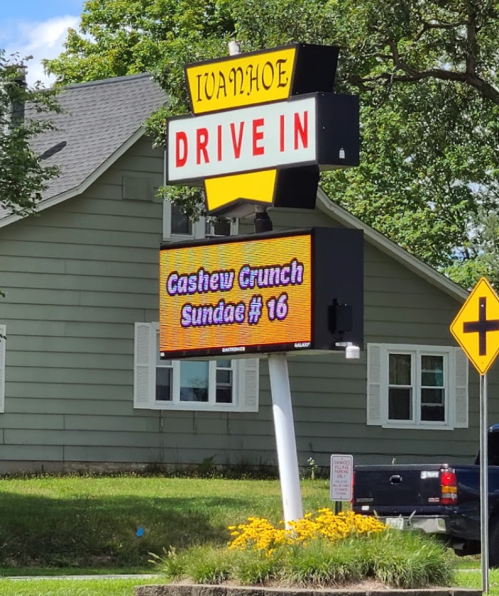 Sign for Ivanhoe Drive-In featuring "Cashew Crunch Sundae #16" with a house in the background.