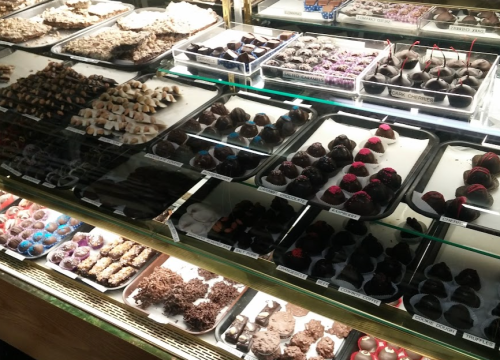 A display case filled with various types of chocolates and confections, showcasing an assortment of shapes and colors.